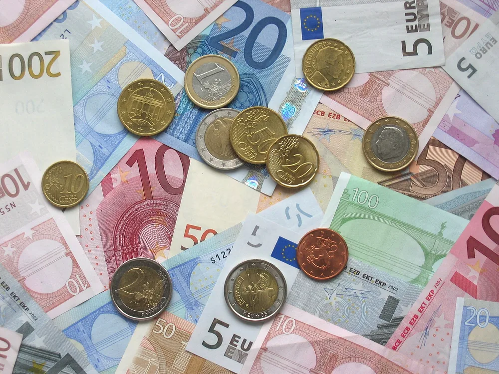 Een tafel vol eurobiljetten van 5 tot 200 euro met daarop verschillende euromunten.
