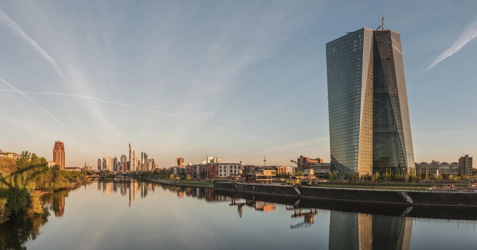 De glazen ECB-toren langs de Main, met de skyline van Frankfurt op de achtergrond.