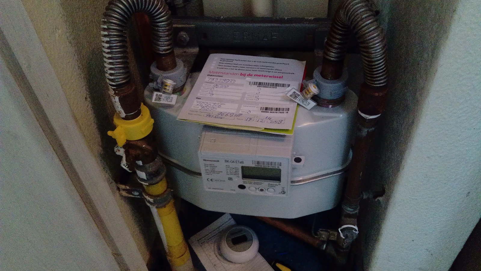 Elektriciteits- en gasmeter met kabels en leidingen in een meterkast.