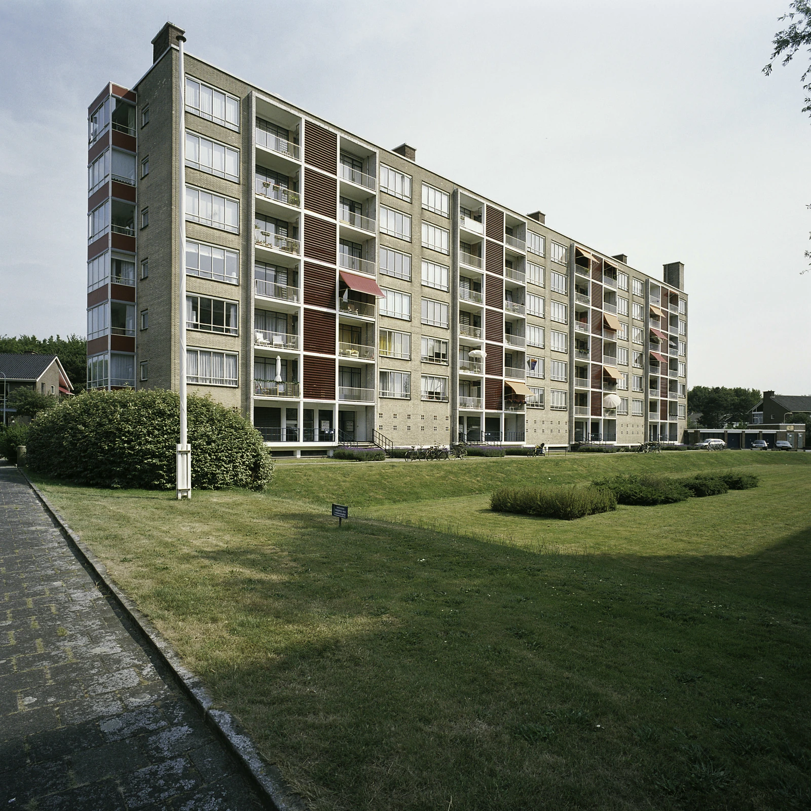 Een portiekflat met balkons naast een grasveld.