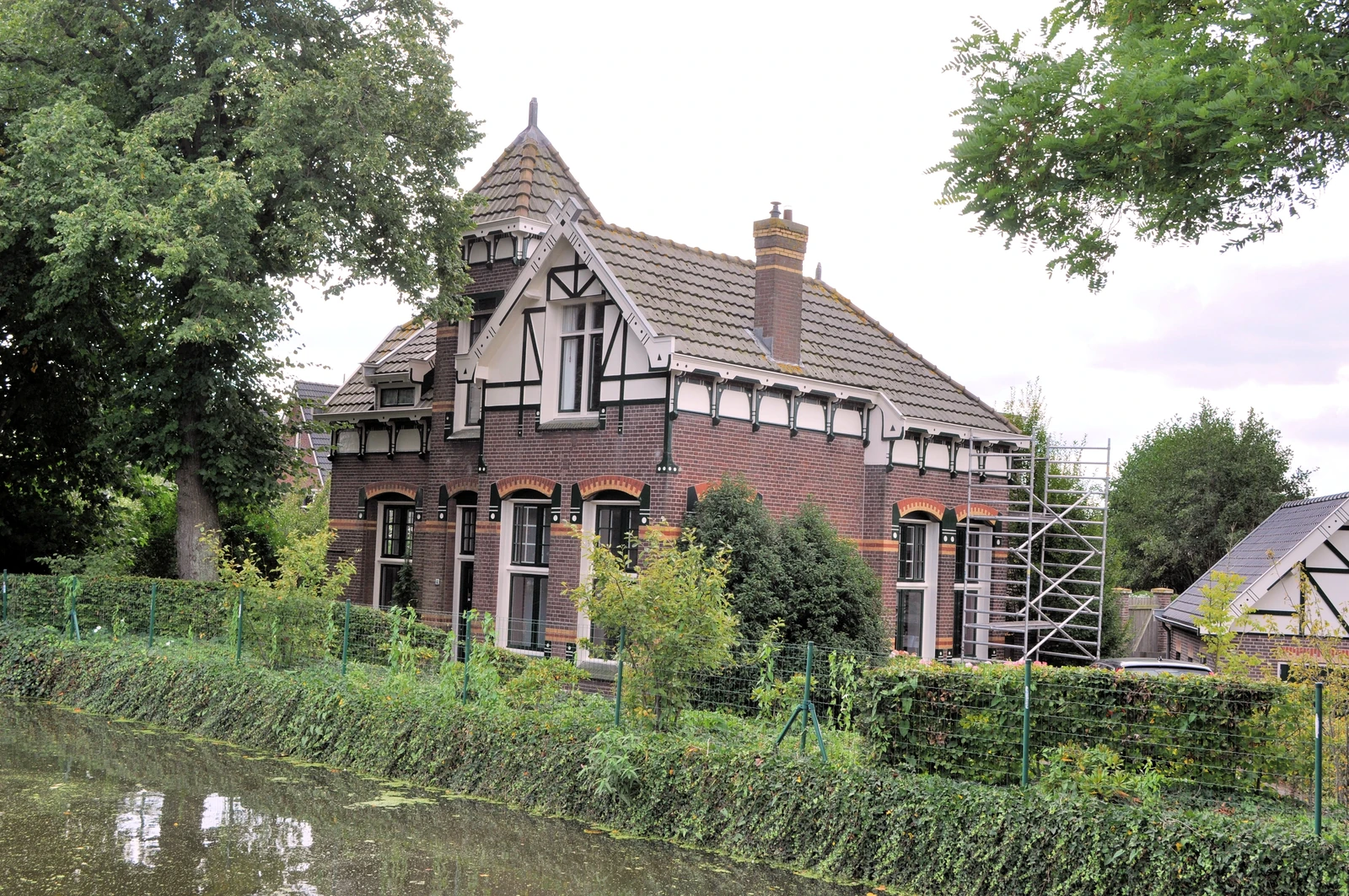 Een vrijstaand huis met een steil dak en een tuin.