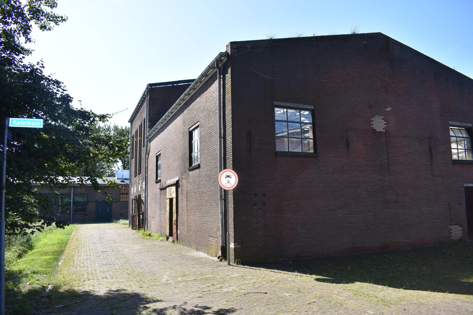 Een bakstenen gebouw naast een pad en begroeiing.